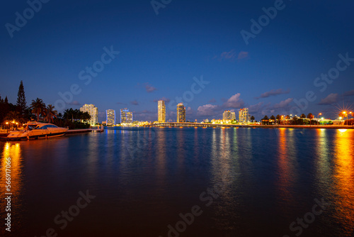 View of Miami at sunset, USA. Miami city skyline panorama at dusk with urban skyscrapers and bridge over sea with reflection.