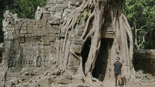 Male Tourist Gazing at The Khmer temple of Ta Som - Tree growing atop the historical main gateway photo