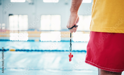 Hands, lifeguard and whistle by swimming pool for water safety, security or ready for rescue indoors. Hand of expert swimmer holding signal tool for warning, safe swim or responsibility for awareness photo