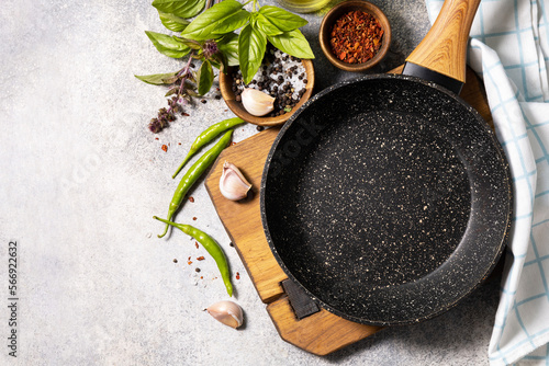 Fototapeta Naklejka Na Ścianę i Meble -  Empty skillet, vegetables, spices and herbs on gray stone background. Food cooking background with Frying pan. View from above. Copy space.