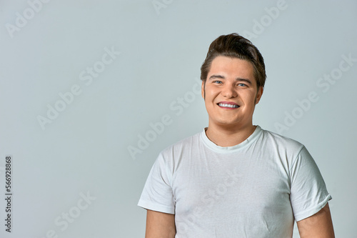 A man in a white T-shirt on a gray background smiles