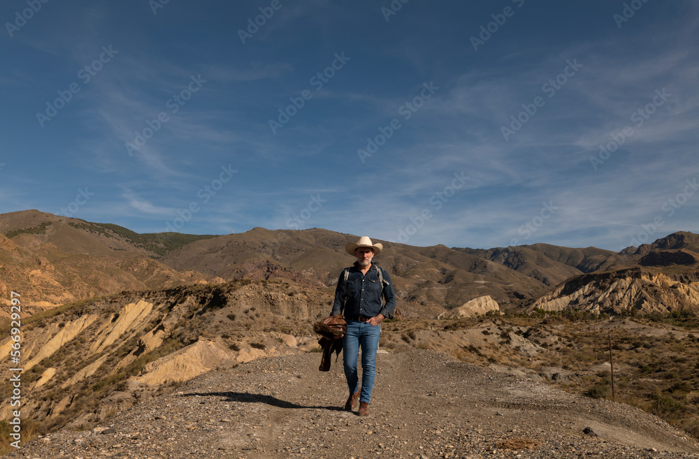Adult man in cowboy hat walking on dirt road in desert. Almeria, Spain