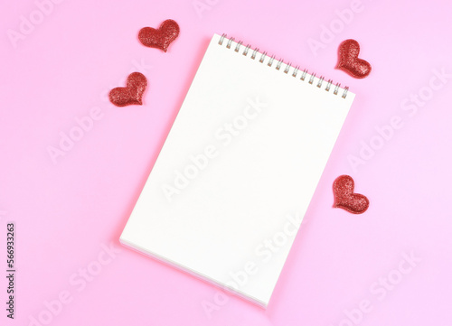 flat lay of opened  notebook with red glitter hearts on pink background with copy space. Love, Valentine's day, memory. © Phuttharak