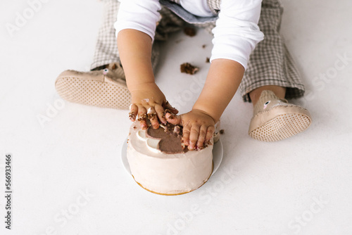Trendy Korean dessert bento cake beige color will be crushed in the hands of a small child. Dessert for the first birthday of the baby