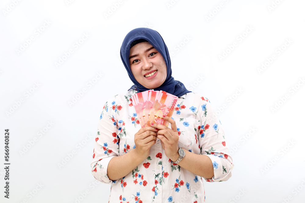 Happy asian muslim woman standing while holding Indonesian banknotes. Isolated on white background Happy asian muslim woman standing while holding Indonesian banknotes. Isolated on white background
