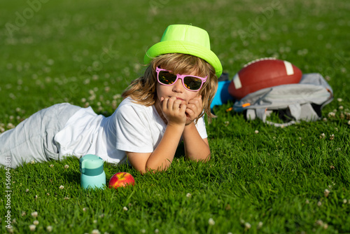Kid relaxing on green meadow. Happy children rest fun outdoors. Kids relaxing in spring park. Boy lying on green grass. © Volodymyr