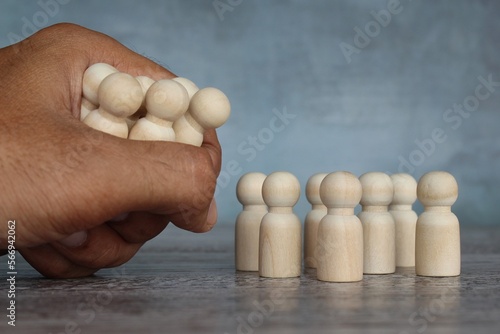 Tablou pe pânză Hand grab wooden dolls. Mass layoffs, downsizing concept.