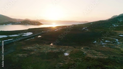 Vehicle driving lake Kleifarvatn long curving road surrounded by lava mountains at sunset, Aerial orbiting view photo