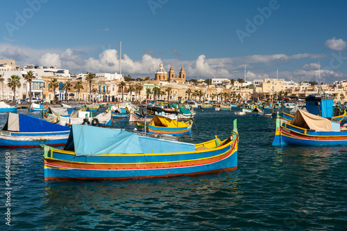 Old Colorful Boats Luzzu in Marsaxlokk harbor at sunny day. Blue sky with clouds