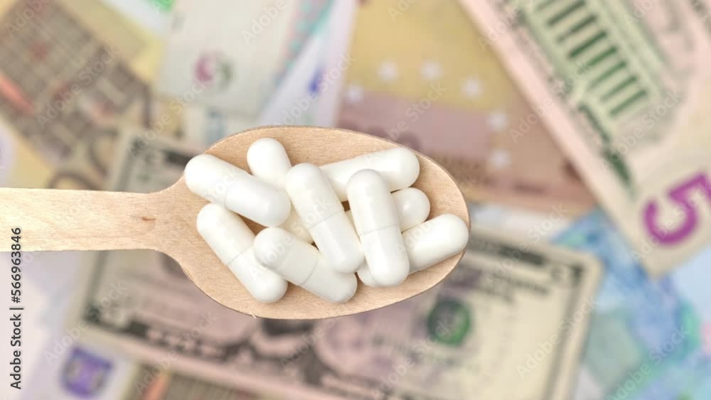 Pills in Wood Spoon on Paper Currency Background. Capsules, Vitamin with Money Cash. Expensive Drugs. Medical or Pharmacy Business, Finance Concept. Cost of Healthy Life. Medicine Price Backdrop. Pills in Wood Spoon on Paper Currency Background. Capsules, Vitamin with Money Cash. Expensive Drugs. Medical or Pharmacy Business, Finance Concept. Cost of Healthy Life. Medicine Price Backdrop.