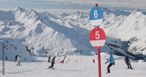 Blue and red piste numbers and snowboarders on slopes at Ischgl ski resort, Paznaun, Austria. Winter, skiing.