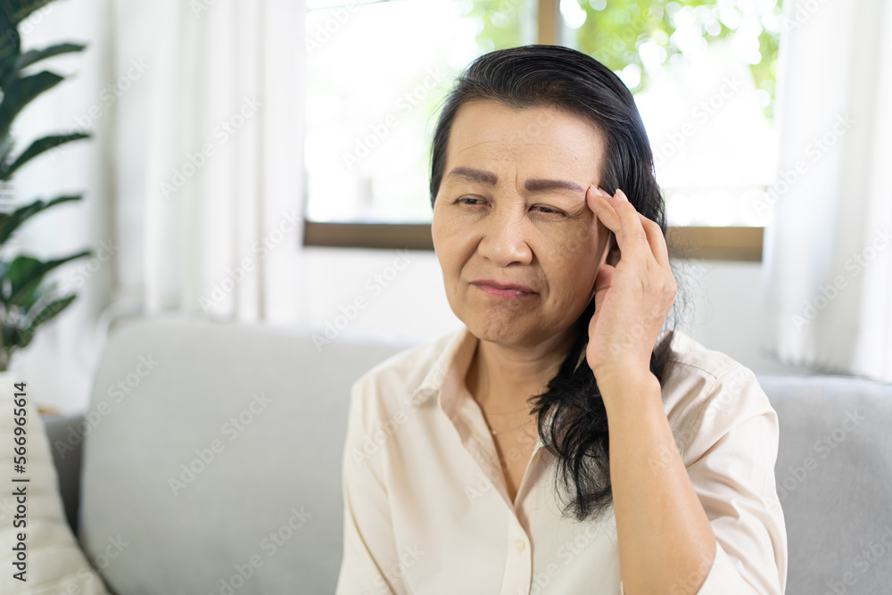Middle age Asian woman touching forehead having headache suffering from. migraine feeling sick or depression Middle age Asian woman touching forehead having headache suffering from. migraine feeling sick or depression