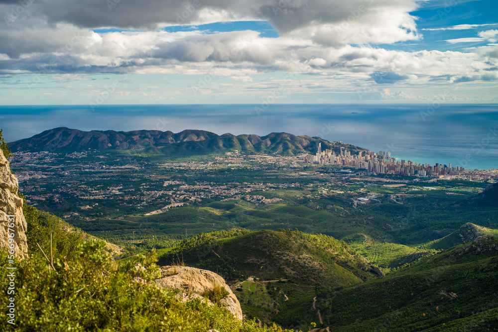 view from Mount Bernia on the trees and valley and apartment buildings of the city of Benidorm and Serra Gelada