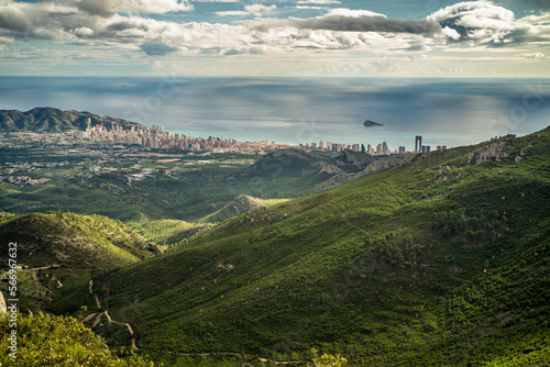 view from Mount Bernia on the trees and valley and apartment buildings of the city of Benidorm and Serra Gelada