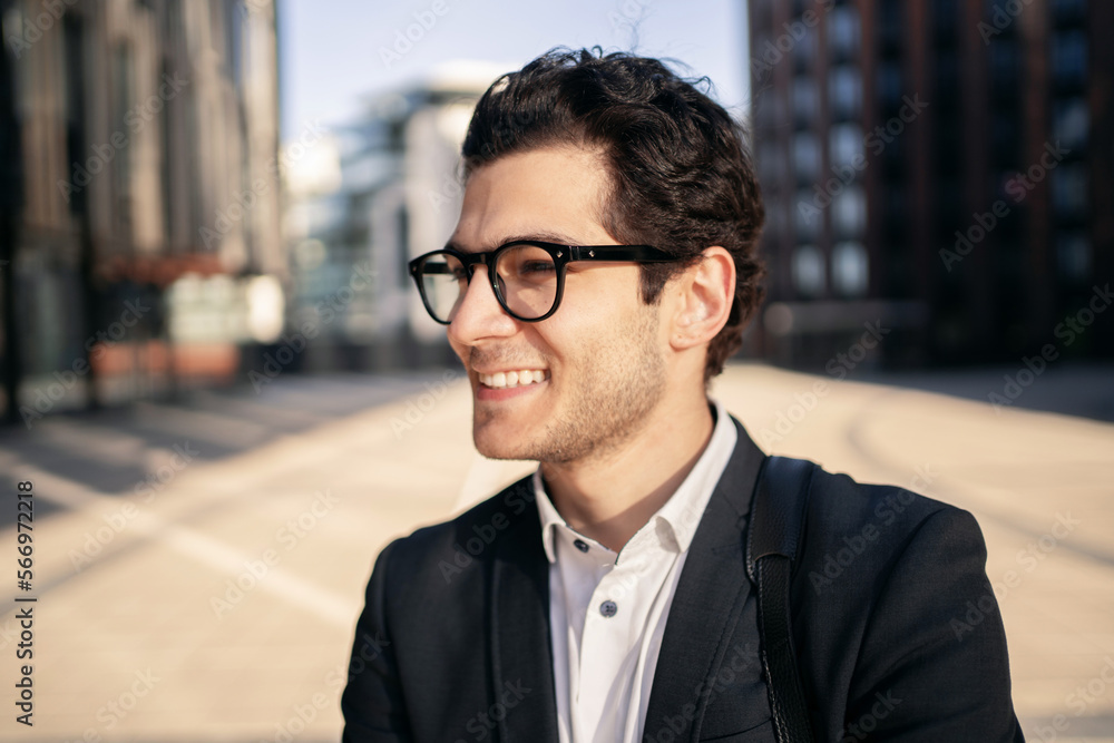 A close portrait of a businessman man in glasses and a formal suit smiling, looking away. A close portrait of a businessman man in glasses and a formal suit smiling, looking away.