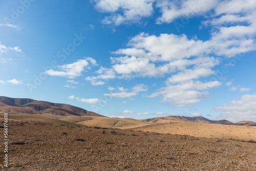 amazing desert landscape with blue sky and white clouds with mountain range in the background. Fuerteventura, Canary Islands, Spain