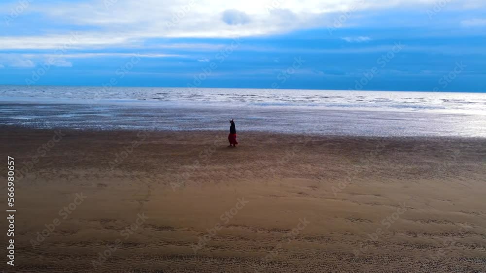 woman walking on the beach. Woman walking alone on yellow beach in front of rippling sea in summer woman walking on the beach. Woman walking alone on yellow beach in front of rippling sea in summer