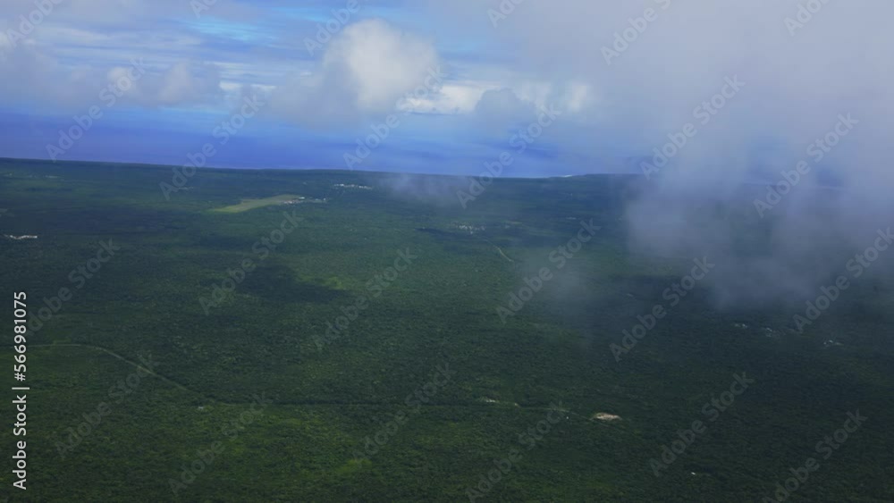 A view from a plane captures the breathtaking sight of flying through the clouds above a tropical forest island, showcasing the beauty of the fluffy clouds contrasting with the green vegetation. A view from a plane captures the breathtaking sight of flying through the clouds above a tropical forest island, showcasing the beauty of the fluffy clouds contrasting with the green vegetation.