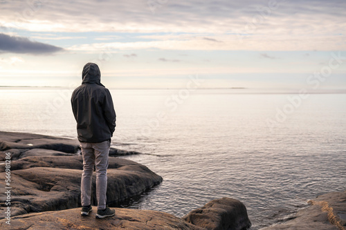 silhouette of a young man on a rocky beach, looking towards the horizon. Fäboda, Jakobstad/Pietarsaari, Finland.  photo