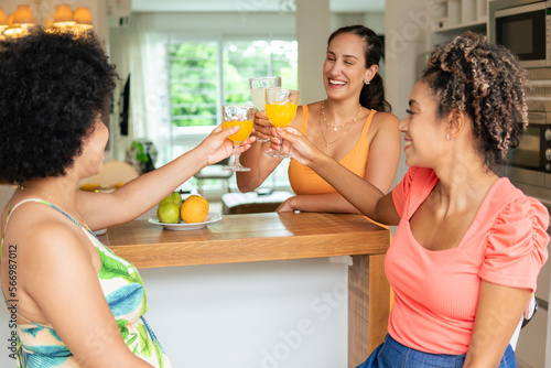 fun friends celebrating with fresh orange juice in kitchen counter