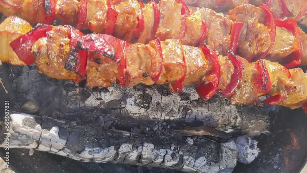 Meat with red pepper on skewers is fried on coals with smoke Meat with red pepper on skewers is fried on coals with smoke