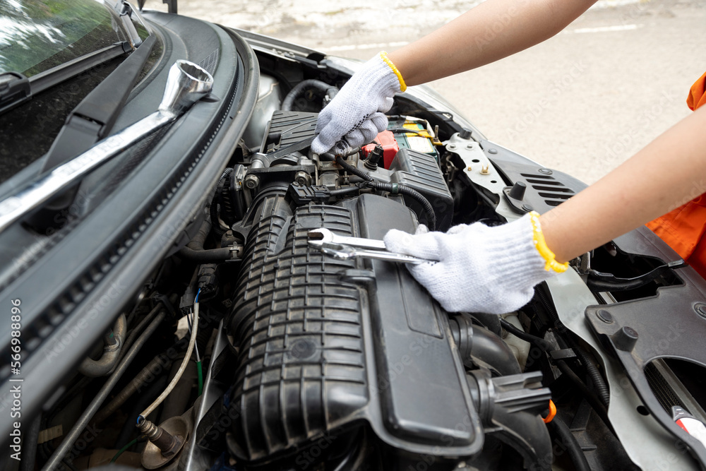 Woman car technician in uniform checking the car engine Woman car technician in uniform checking the car engine