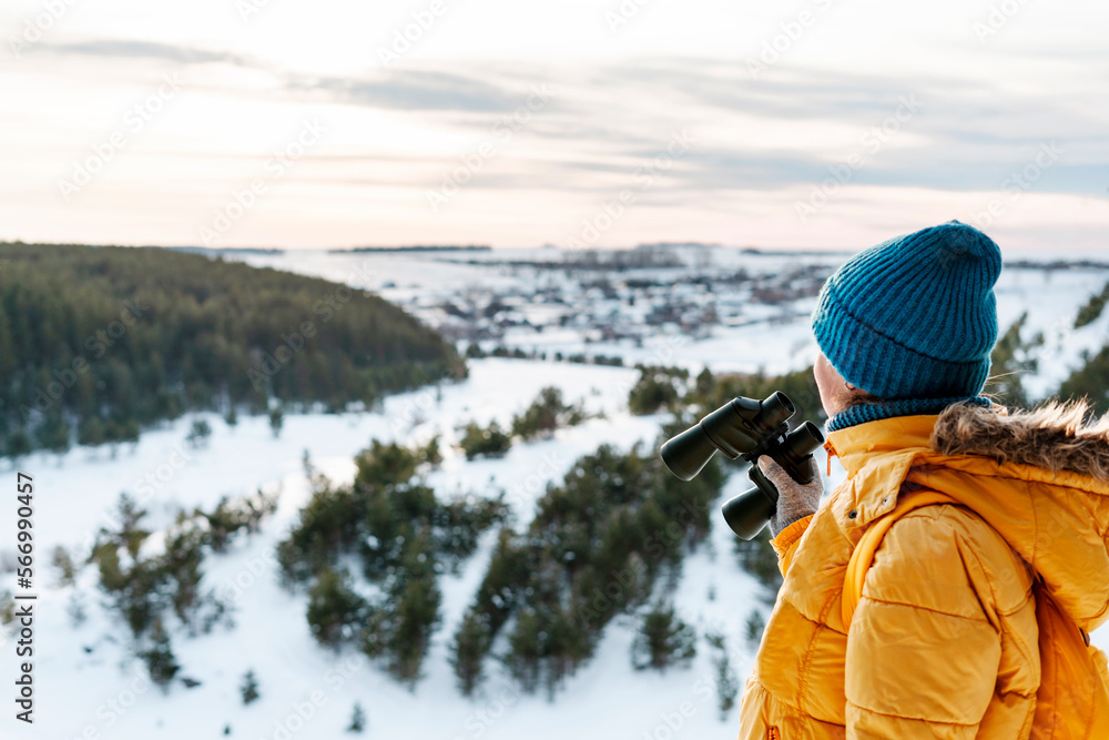 Young woman in yellow with binoculars looking at birds on mountain against winter snowy river and forest Birdwatching, zoology ecology Research in nature, observation of animals Ornithology copy space Young woman in yellow with binoculars looking at birds on mountain against winter snowy river and forest Birdwatching, zoology ecology Research in nature, observation of animals Ornithology copy space