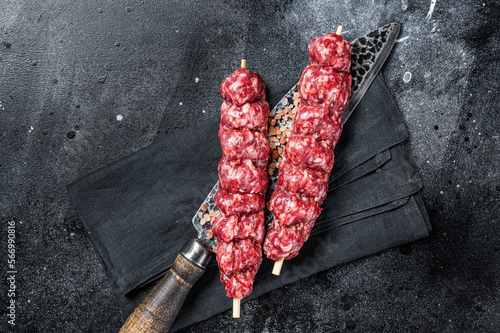 Raw kofta, kofte kebab Skewers with beef and lamb meat and spices. Black background. Top view