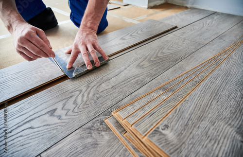 Canvas Print Man preparing laminate plank for floor installation in apartment under renovation