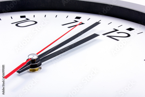 Midnight is coming. Black and white office clock with a red pointer on a gray background.