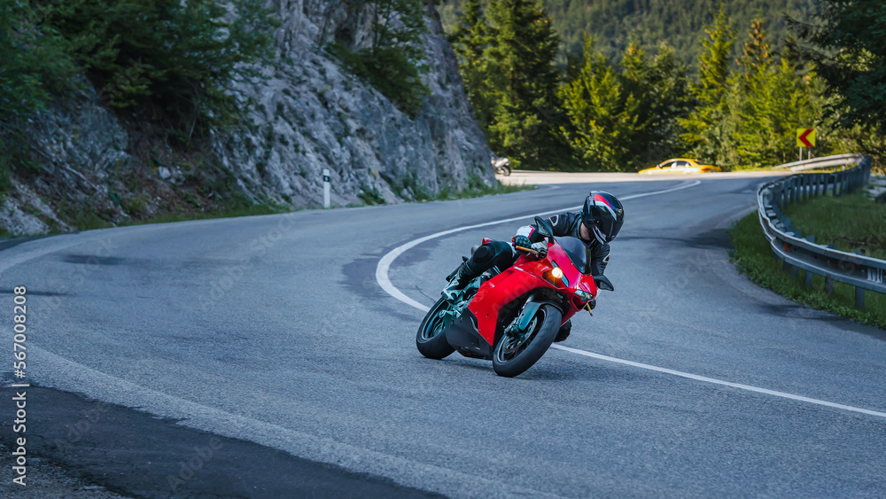 Rider  in black helmet on red sportbike motorcycle in mountains