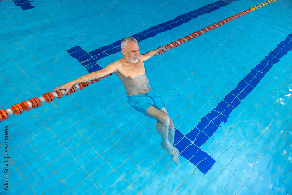 Gray-haired bearded swimmer looking contented at the swimming pool