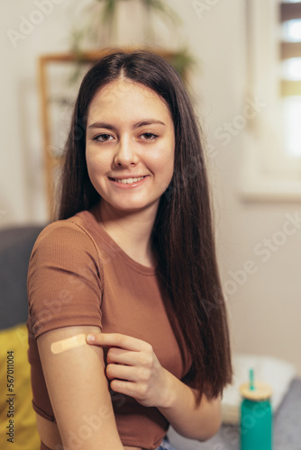 Cheerful teenage girl having plaster on arm .Virus protection. Covid-19 vaccination. HPV vaccine photo