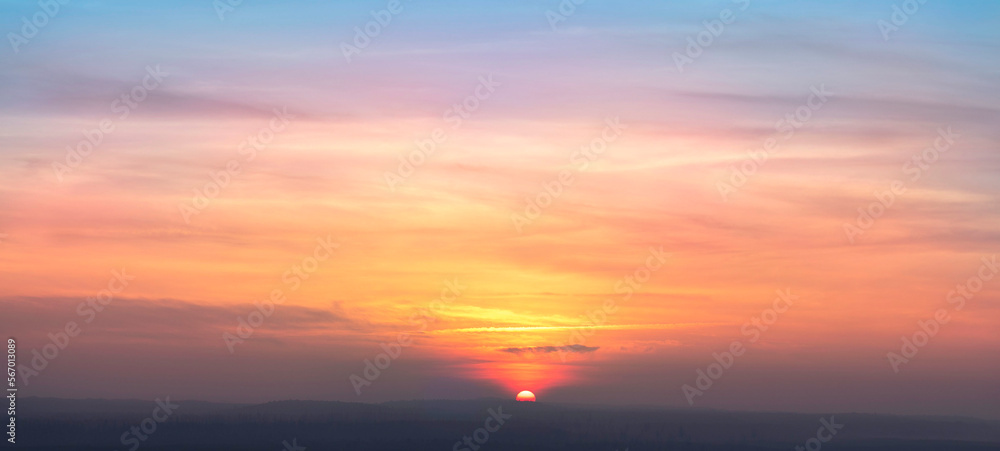 Real amazing panoramic sunrise or sunset sky with gentle colorful clouds. Long panorama, crop it. Evening sky scene with golden light from the setting sun