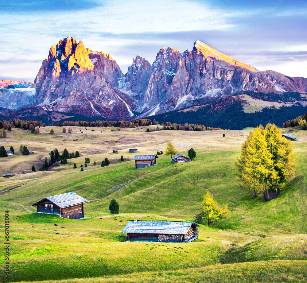 Mystic fantastic spring landscape with wooden houses in the backgroundin Alpe di Siusi in the Dolomites Alps. Exotic amazing places.