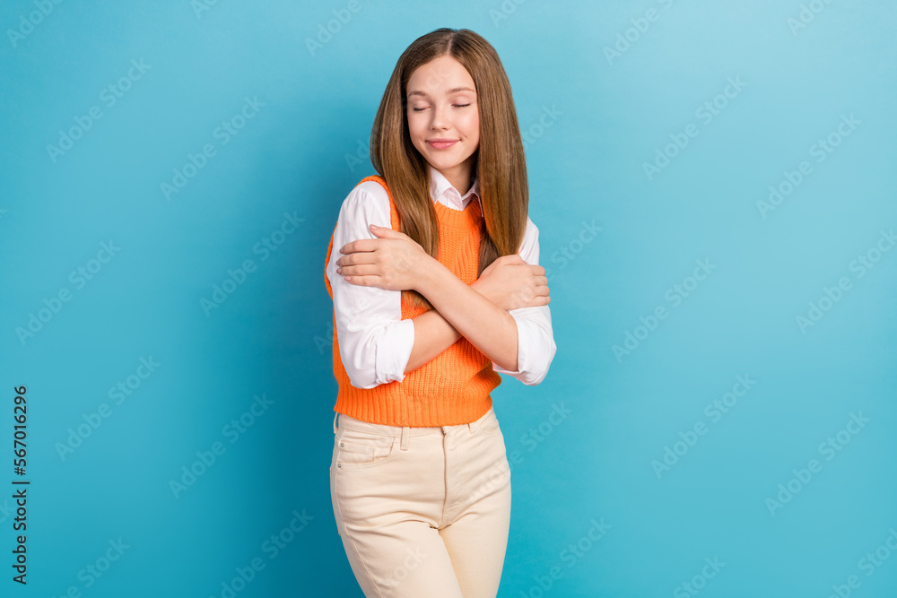 Photo of cute lovely lady wear trendy clothes eyes closed hugging herself isolated on blue color background Photo of cute lovely lady wear trendy clothes eyes closed hugging herself isolated on blue color background