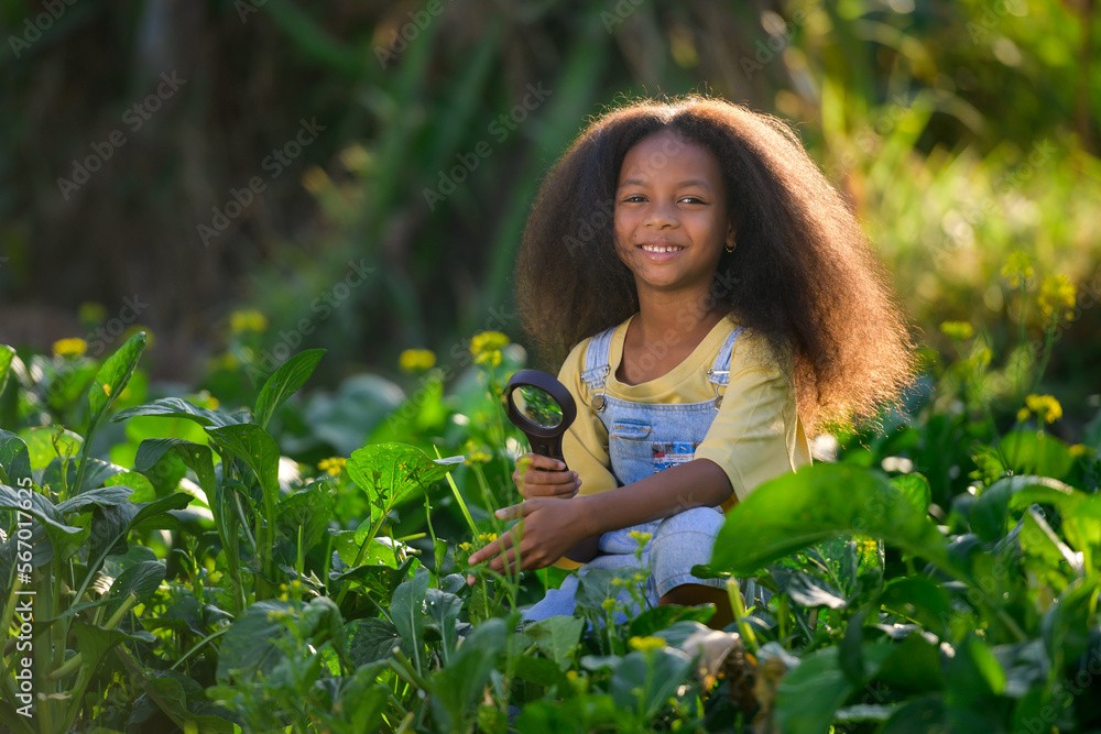 African girl holding a magnifying glass to look at insects and learn about agriculture in a rural vegetable garden for education African girl holding a magnifying glass to look at insects and learn about agriculture in a rural vegetable garden for education