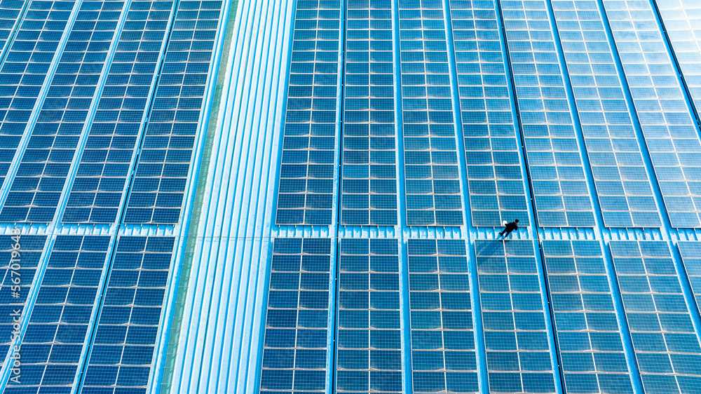 A person is checking solar panels on the roof of a building
