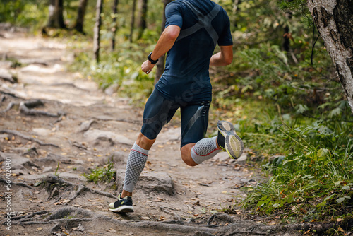 фотографія male athlete running in forest in compression calf sleeve