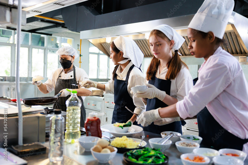 Senior asian woman chef teach student. Cooking class. culinary classroom. group of happy young woman multi-ethnic students are focusing on cooking lessons in a cooking school. Senior asian woman chef teach student. Cooking class. culinary classroom. group of happy young woman multi-ethnic students are focusing on cooking lessons in a cooking school.