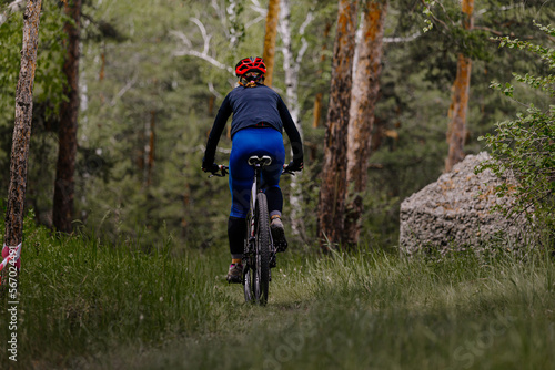 back woman riding mountain bike on forest trail
