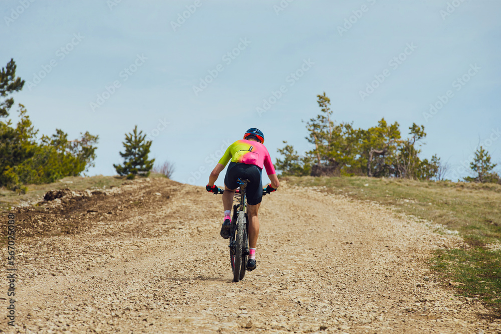 male cyclist riding uphill trail on mountain bike