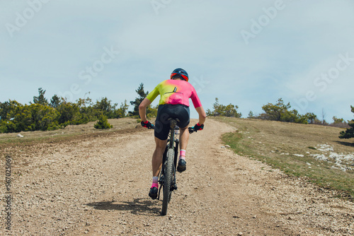 back male athlete on mountain bike riding uphill on trail