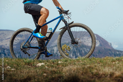 closeup man on mountain bike riding trail in background of mountain