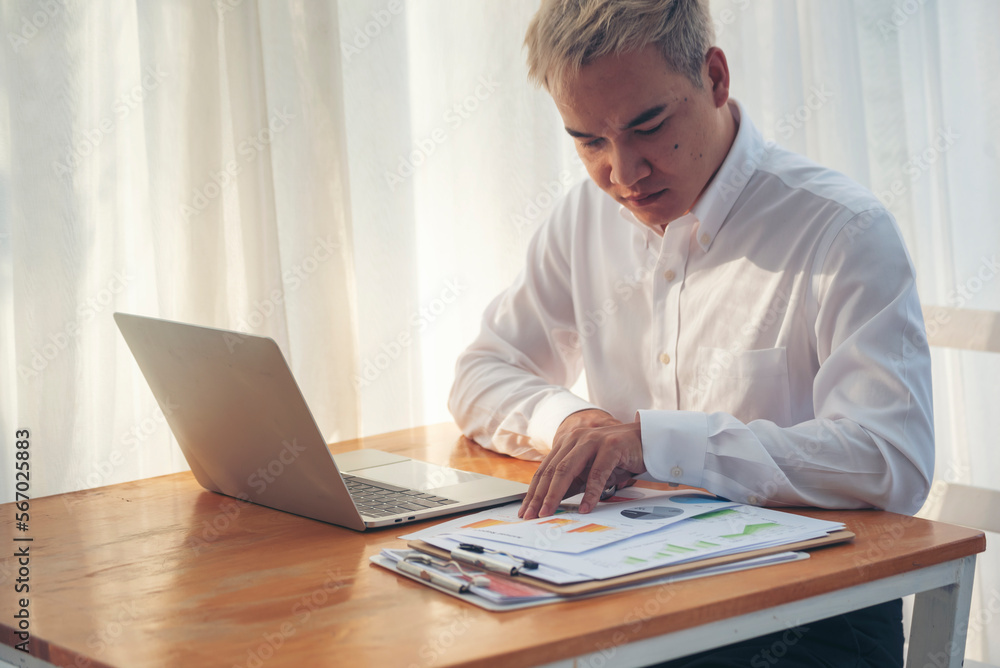 Fototapeta premium Asian Businessman type keyboard write financial graph chart Planning marketing data. Man hands using laptop at office desk reading spreadsheet excel finance document. Business men working home office