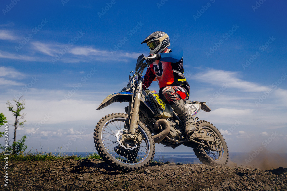 male rider in enduro motorcycle on top mountain
