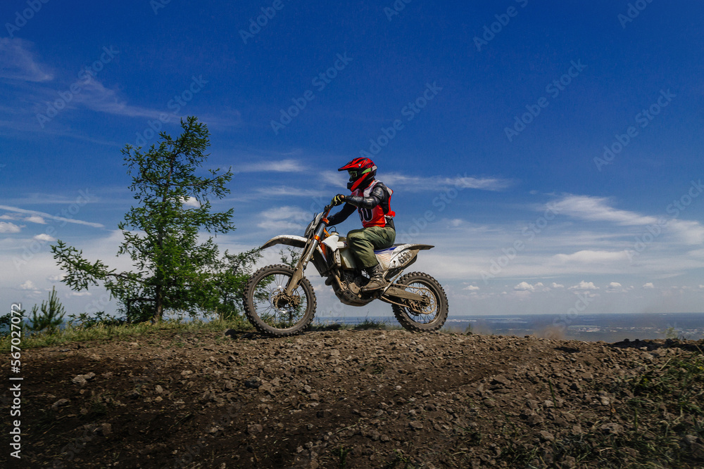 enduro motorcycle rider on mountain in background blue sky