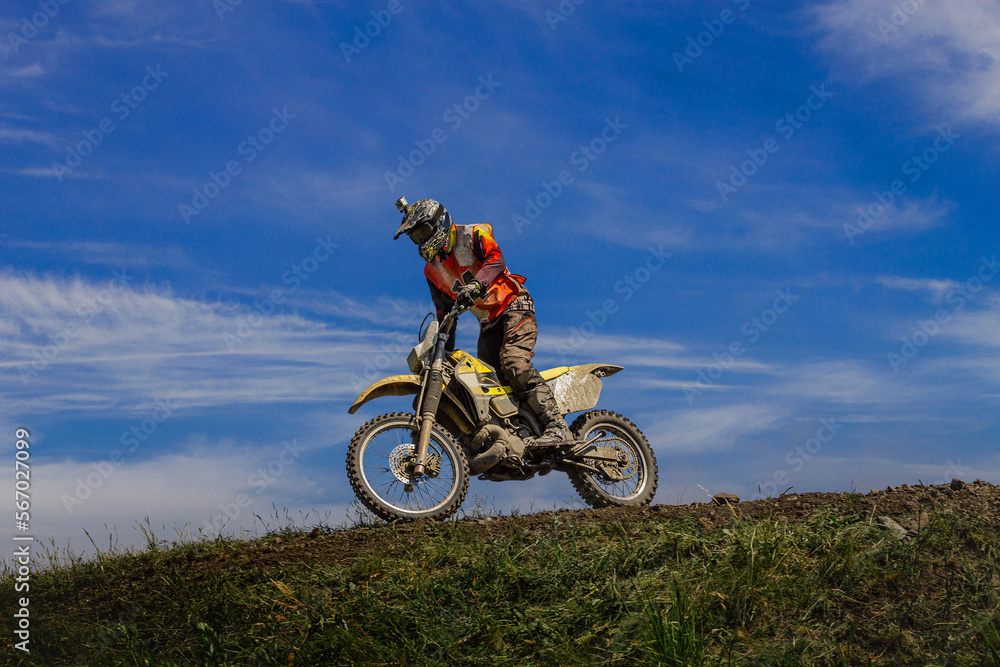 enduro motorcycle racer on mountain in background blue sky