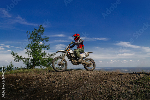 enduro motorcycle rider on mountain in background blue sky