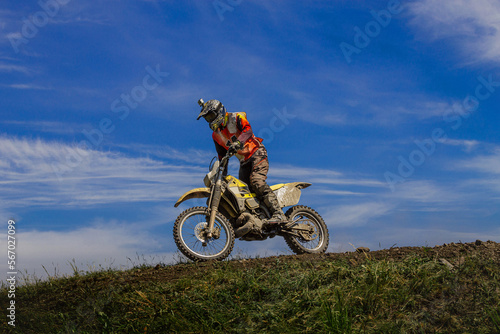 enduro motorcycle racer on mountain in background blue sky